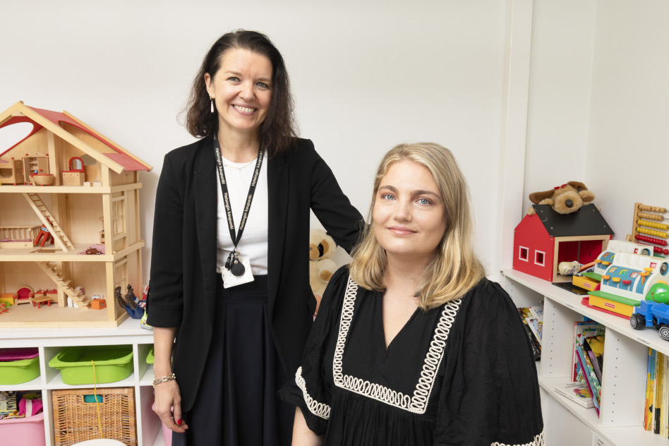 Kaksi naista vierekkäin, toinen istuu, toinen seisoo