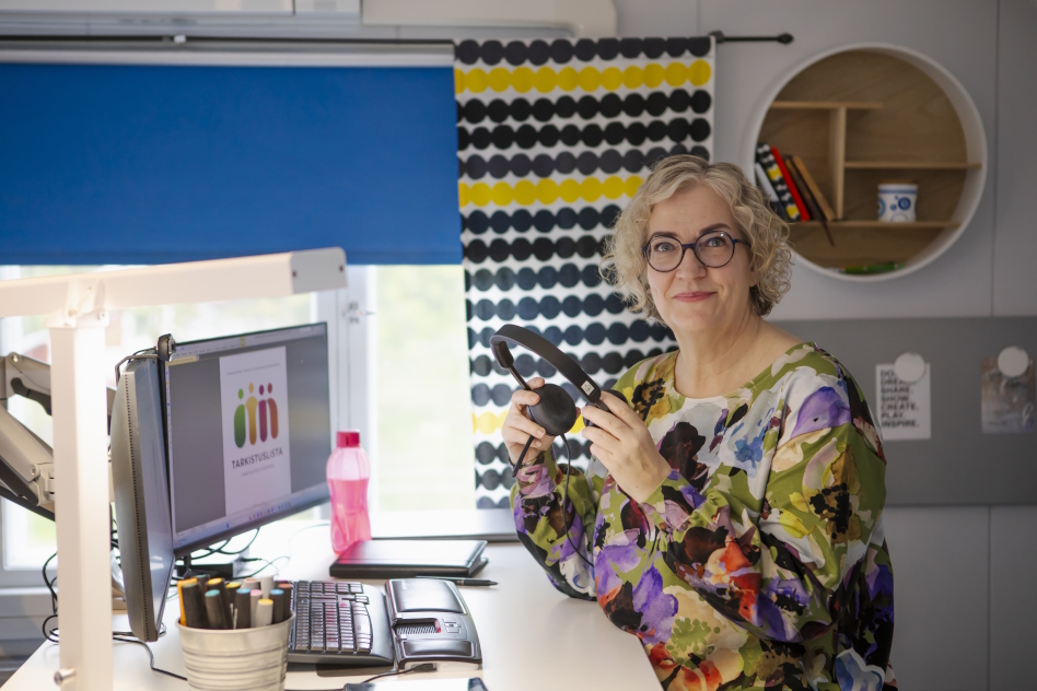 Nainen tietokoneen ääressä kuulokkeiden kanssa.