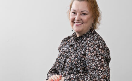 Nainen kirjavassa puserossa pöydän ääressä