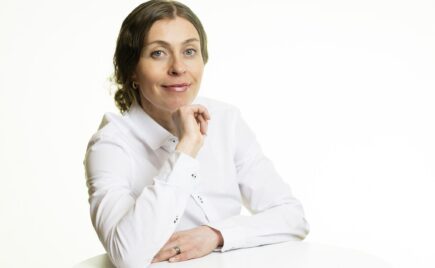 Tummahiuksinen nainen valkeassa puserossa