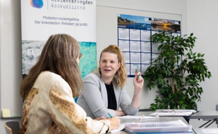 Ponihäntäpäinen nainen juttelee toiselle naiselle, joka on häneen selin.