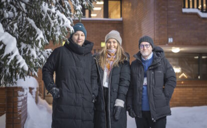 Kaksi naista ja yksi mies seisovat talvivaatteissa talon edessä