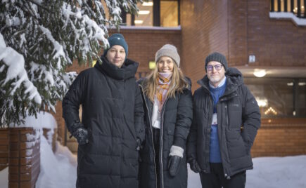 Kaksi naista ja yksi mies seisovat talvivaatteissa talon edessä