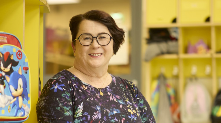 Silmälasipäinen nainen päiväkodin eteisessä