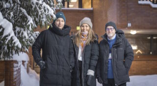 Kaksi naista ja yksi mies seisovat talvivaatteissa talon edessä