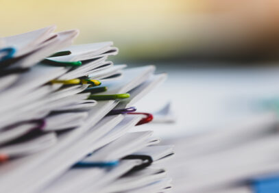 Paperipino, joka on nivottu yhteen useammalla värikkäällä klemmarilla.