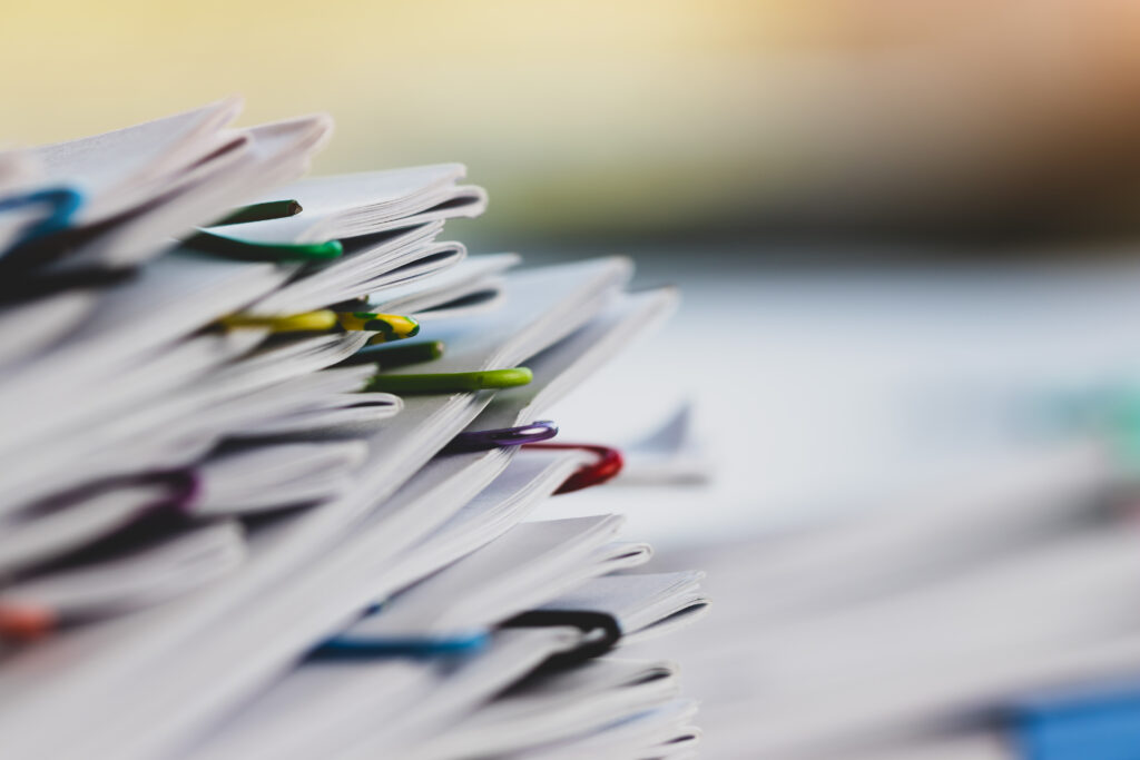 Paperipino, joka on nivottu yhteen useammalla värikkäällä klemmarilla.