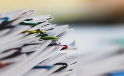 Paperipino, joka on nivottu yhteen useammalla värikkäällä klemmarilla.