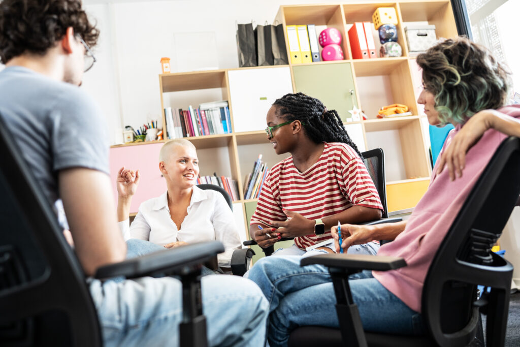 Kuvassa neljä ihmistä istuu vastakkain juttelemassa toimiston omaisessa huoneessa.