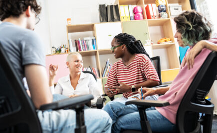 Kuvassa neljä ihmistä istuu vastakkain juttelemassa toimiston omaisessa huoneessa.