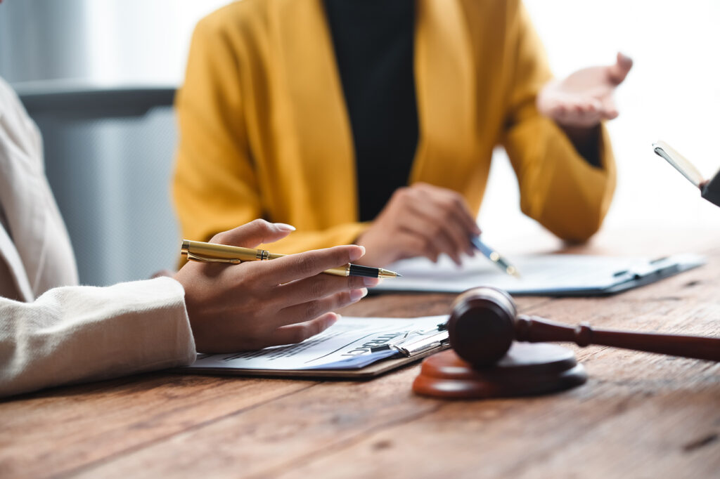 Kaksi ihmistä pöydän äärellä edessään papereita ja puheenjohtajan nuija