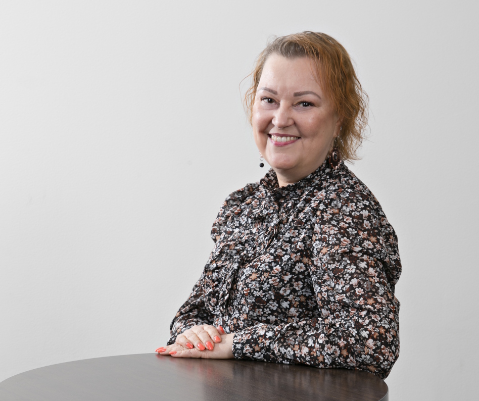 Nainen kirjavassa puserossa pöydän ääressä