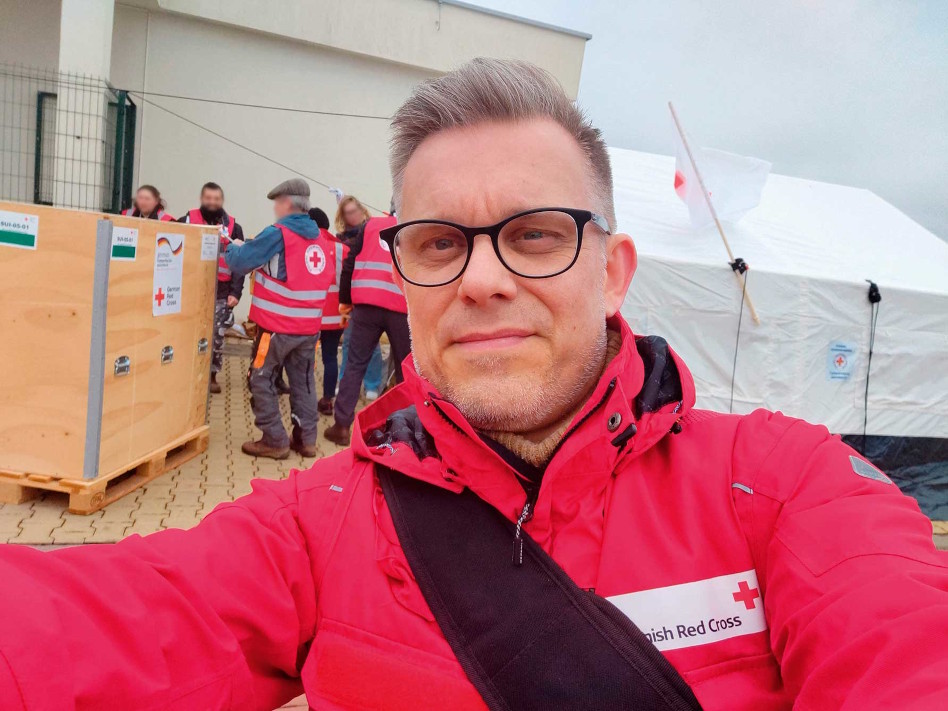 Silmälasipäinen mies punaisessa Punaisen Ristin puserossa