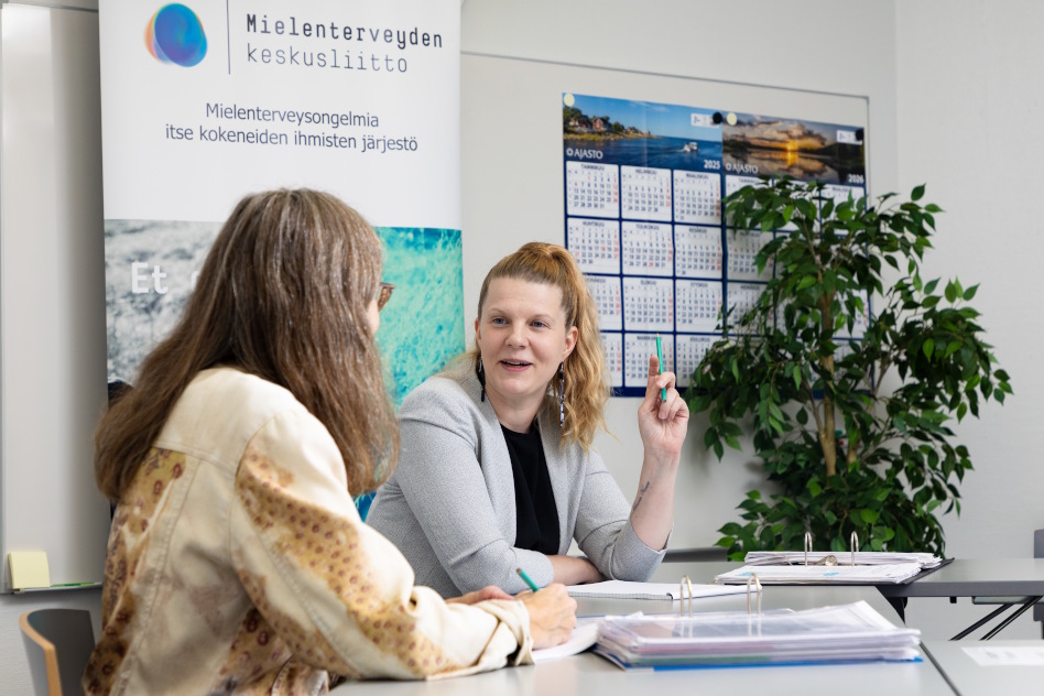 Ponihäntäpäinen nainen juttelee toiselle naiselle, joka on häneen selin.