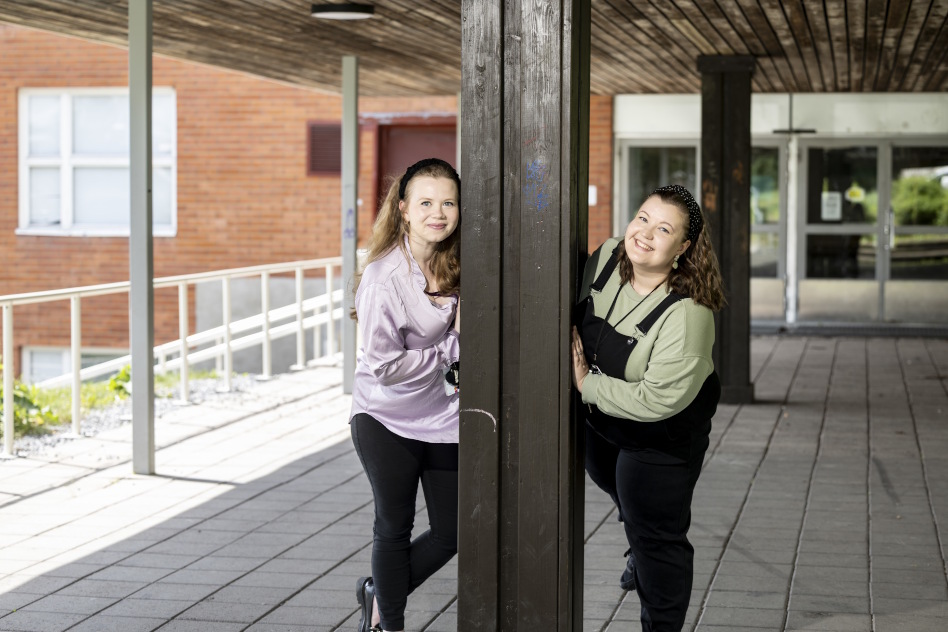 Kaksi nuorta naista oven molemmin puolin
